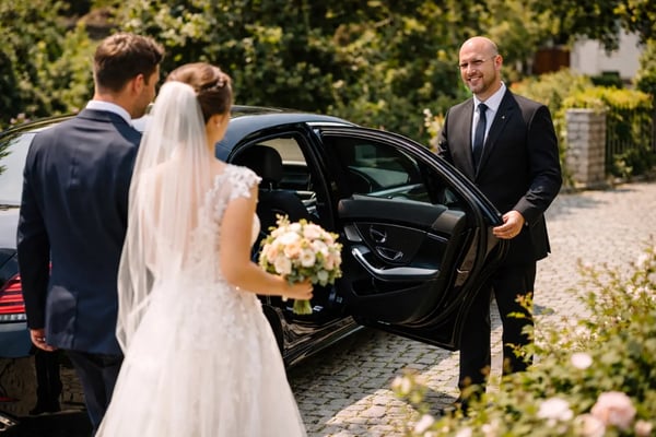 Ein Chauffeur von Antares Driver Services öffnet dem Brautpaar die Tür zur Hochzeitslimousine