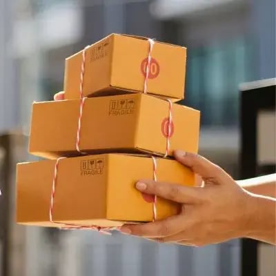 Ein Paketzusteller hält mehrere Pakete in der Hand