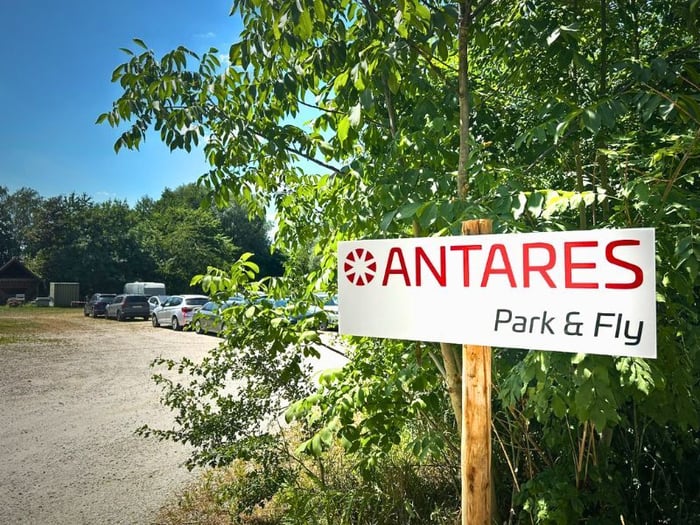 Firmenschild und parkende Autos auf der Outdoorfläche von Antares Park and Fly